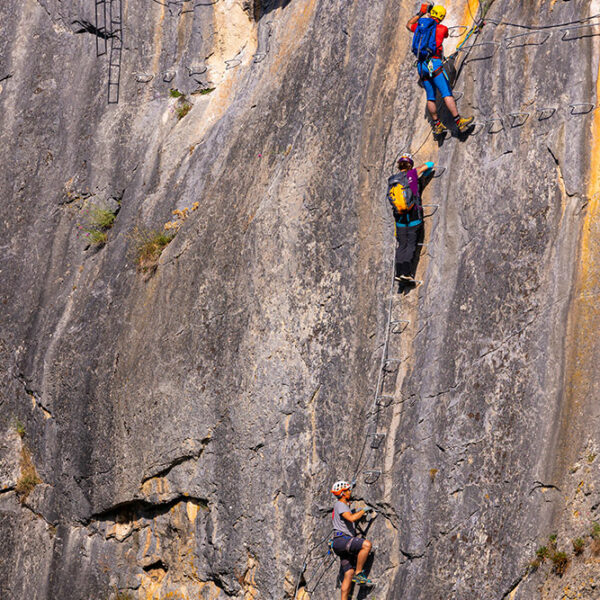Escursionistas escalando una pared rocosa en la Vía Ferrata de Cistierna